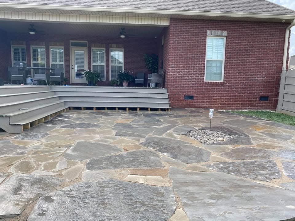 Flagstone hardscape patio beside a brick home